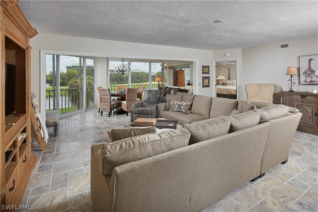 living room with a textured ceiling, a water view, and ceiling fan