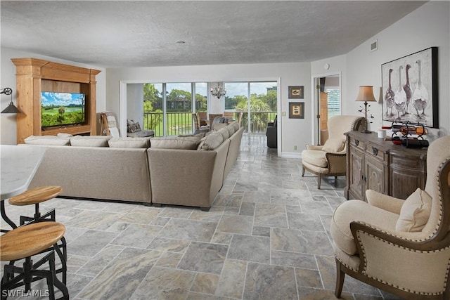 living room featuring visible vents, baseboards, an inviting chandelier, stone finish flooring, and a textured ceiling