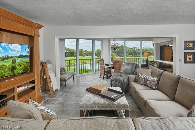 living room featuring a water view, a healthy amount of sunlight, and a textured ceiling