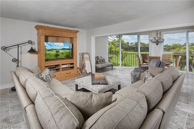 living room featuring stone tile flooring, a notable chandelier, baseboards, and a textured ceiling