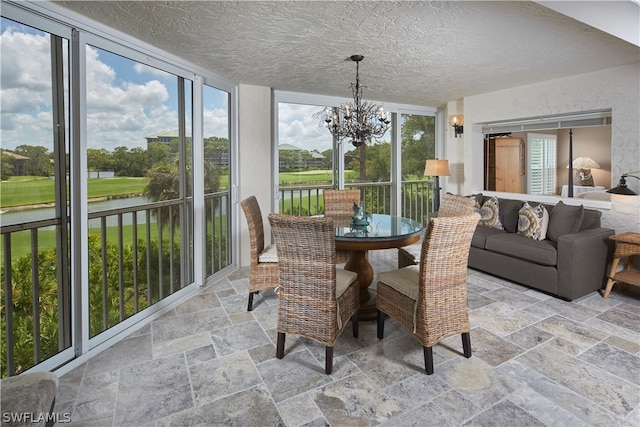 sunroom / solarium featuring a water view and a chandelier