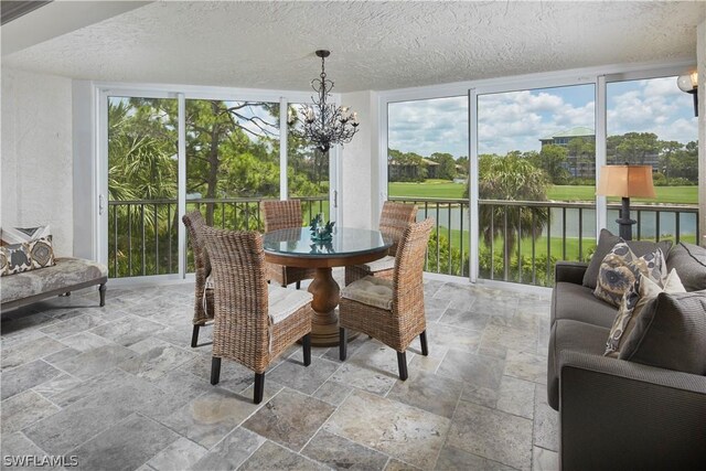 sunroom / solarium featuring a water view and an inviting chandelier