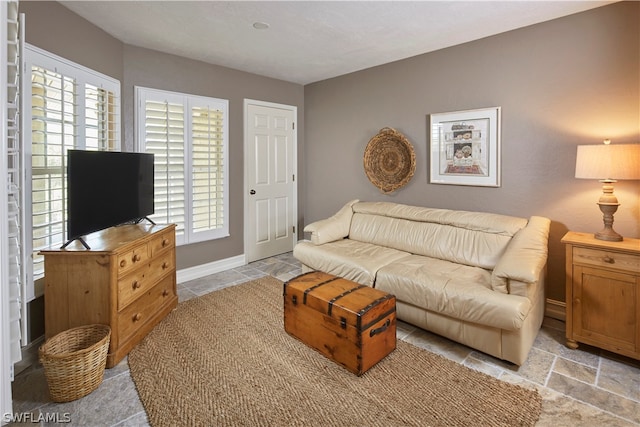 living room featuring a healthy amount of sunlight, baseboards, and stone finish floor