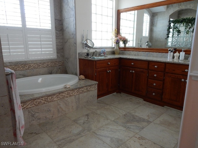 bathroom featuring vanity, tile patterned floors, and tiled tub