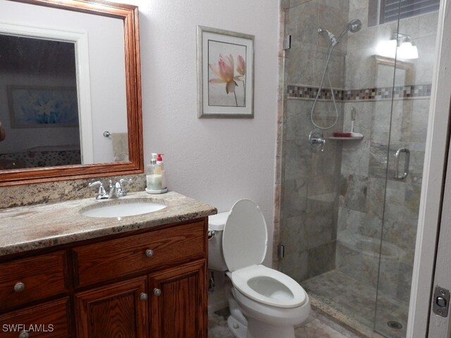 bathroom with an enclosed shower, vanity, and toilet