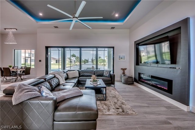 living room featuring light hardwood / wood-style floors, a healthy amount of sunlight, and a raised ceiling