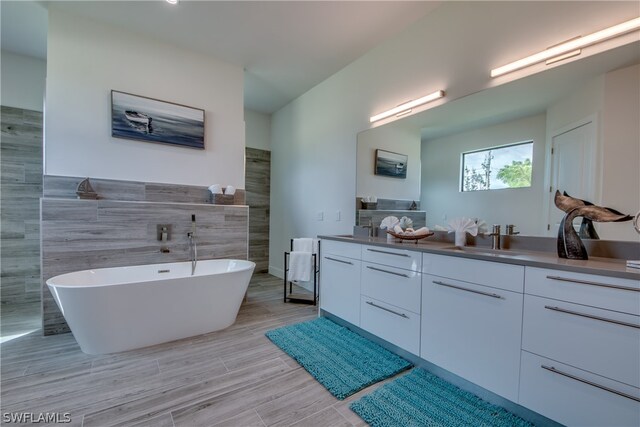 bathroom with tile walls, a bathing tub, tile floors, and double vanity