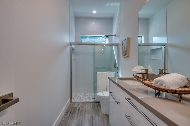 bathroom with wood-type flooring, vanity, toilet, and a shower with door