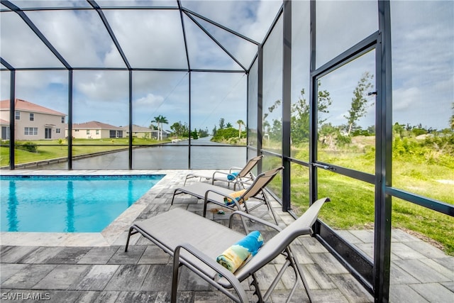 view of swimming pool with a lawn, glass enclosure, and a patio