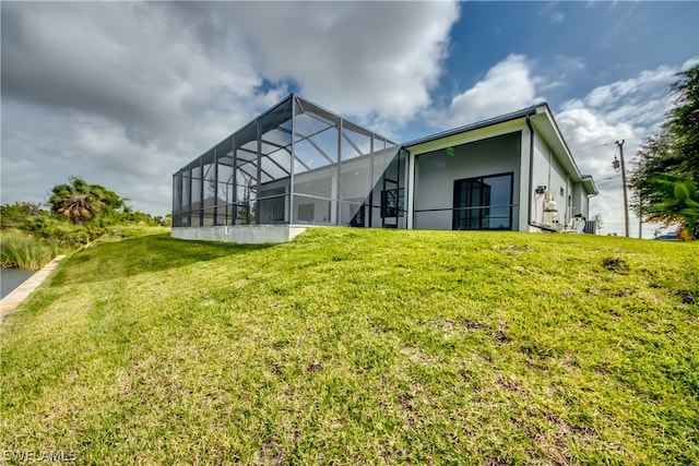 rear view of house with a lanai and a lawn