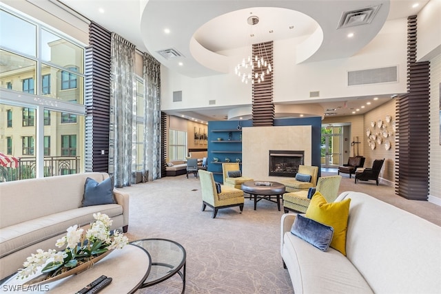 carpeted living room featuring a chandelier, a towering ceiling, and a healthy amount of sunlight