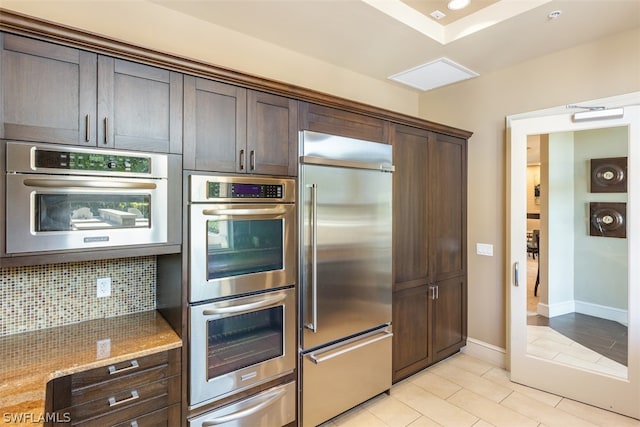 kitchen featuring dark brown cabinetry, light stone countertops, and appliances with stainless steel finishes