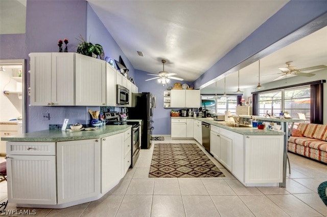 kitchen with vaulted ceiling, appliances with stainless steel finishes, ceiling fan, and white cabinetry