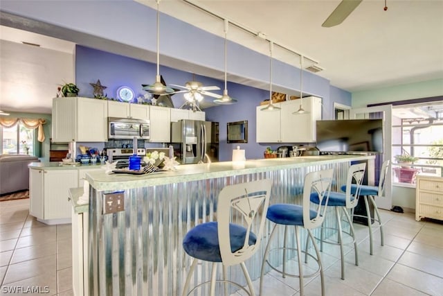 kitchen featuring plenty of natural light, ceiling fan, stainless steel appliances, and light tile floors