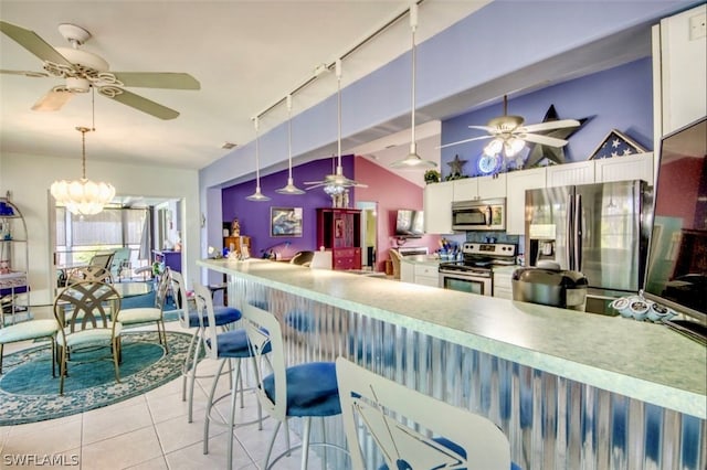 kitchen featuring appliances with stainless steel finishes, white cabinets, decorative light fixtures, rail lighting, and vaulted ceiling