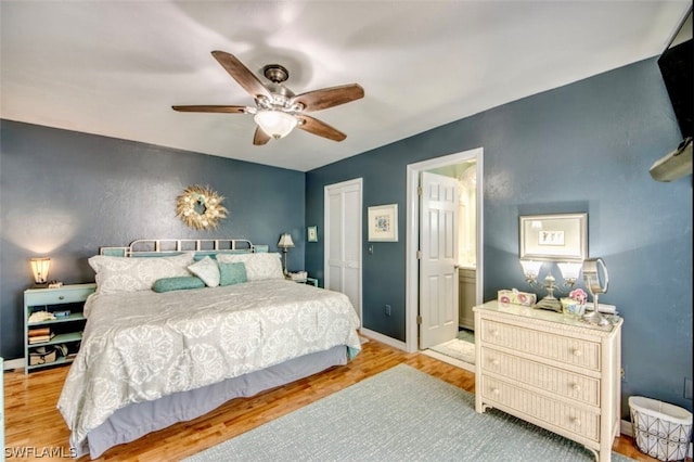 bedroom with ensuite bath, light hardwood / wood-style flooring, ceiling fan, and a closet