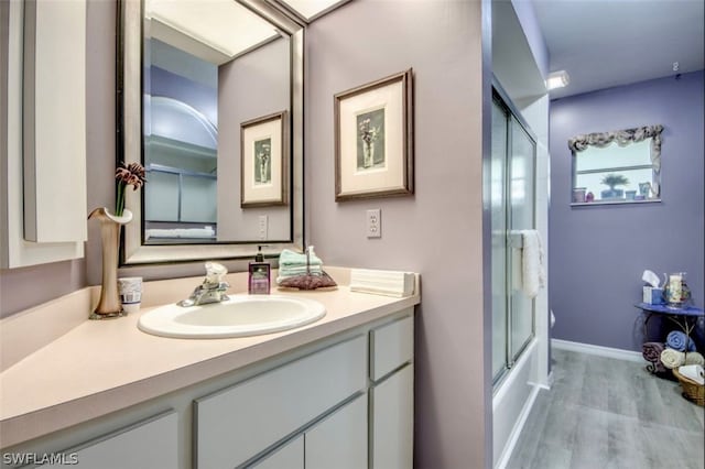 bathroom featuring shower / bath combination with glass door, hardwood / wood-style flooring, and vanity with extensive cabinet space