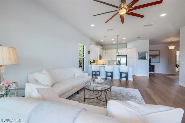 living room with hardwood / wood-style floors and ceiling fan with notable chandelier