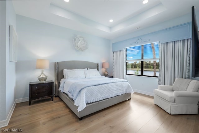 bedroom featuring a tray ceiling and hardwood / wood-style flooring