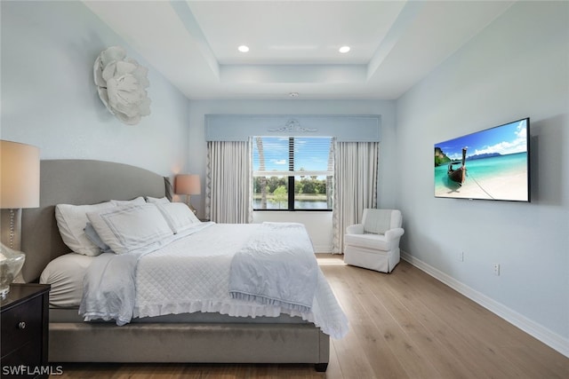 bedroom featuring a tray ceiling and light hardwood / wood-style floors