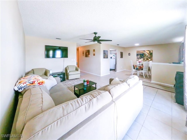 living room featuring ceiling fan, light tile patterned flooring, and a textured ceiling