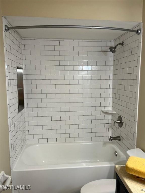 full bathroom featuring vanity, tiled shower / bath, and toilet