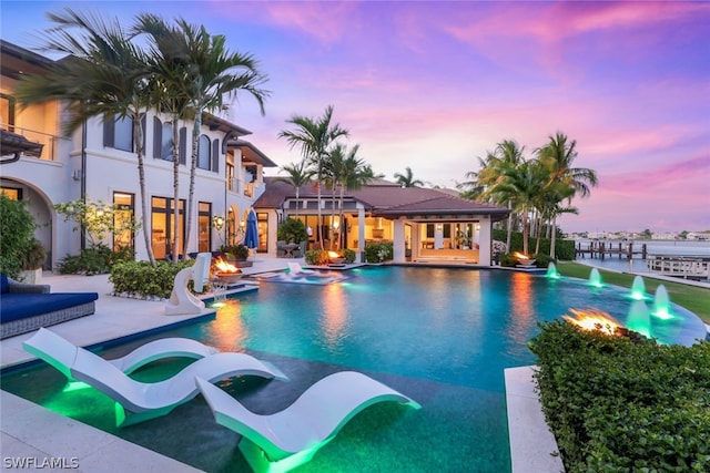 pool at dusk featuring a patio area and a water slide