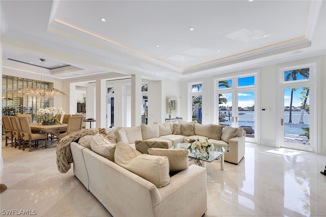 tiled living room featuring a tray ceiling, crown molding, and a water view