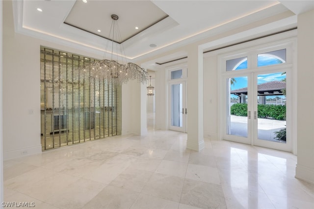 tiled spare room with a notable chandelier, french doors, and a raised ceiling