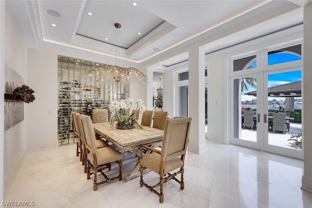 tiled dining area featuring a tray ceiling, french doors, and a chandelier