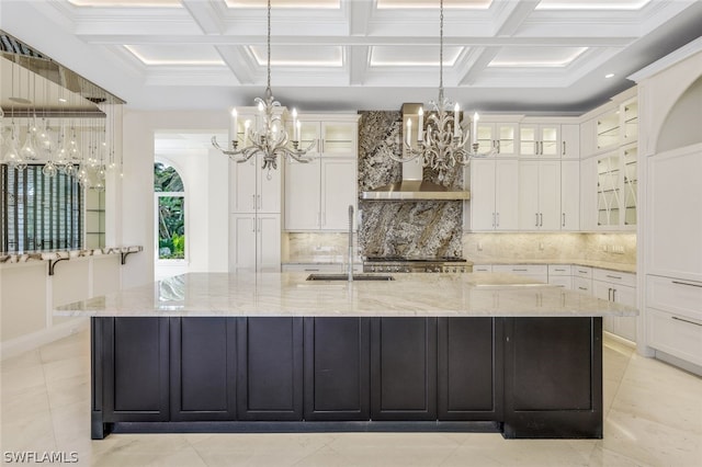 kitchen with tasteful backsplash, coffered ceiling, pendant lighting, and wall chimney exhaust hood