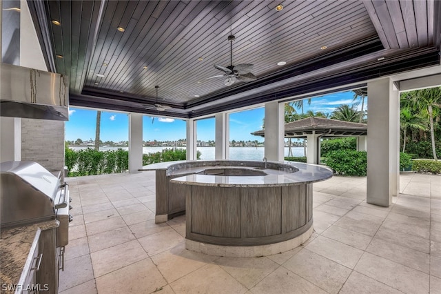 view of patio / terrace with a hot tub, ceiling fan, and a water view