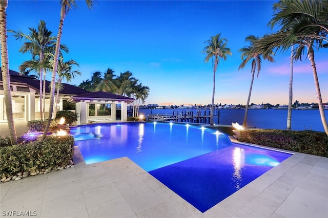 pool at dusk featuring a water view