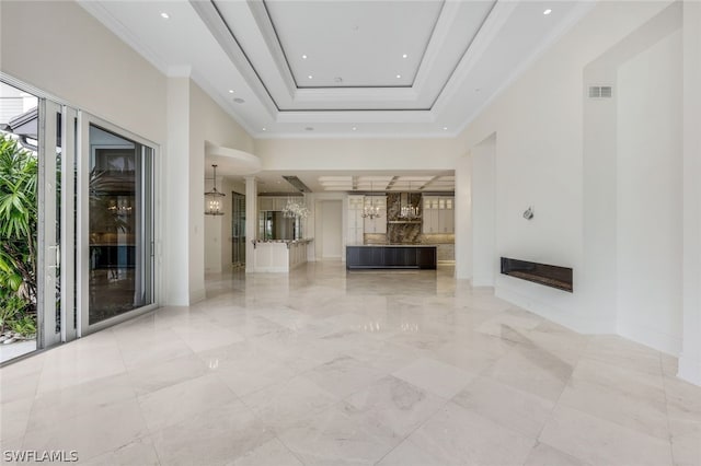 unfurnished living room featuring light tile flooring and a raised ceiling