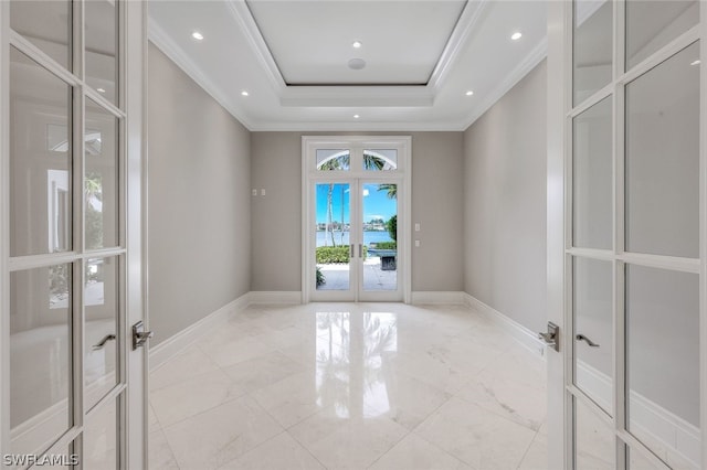 tiled empty room with a raised ceiling, french doors, and ornamental molding