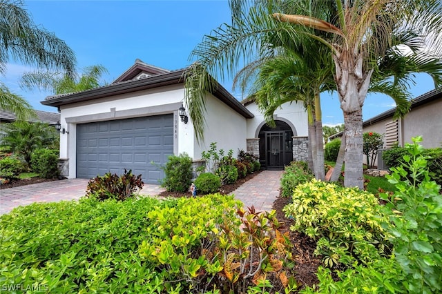 view of front of property with a garage, stone siding, decorative driveway, and stucco siding