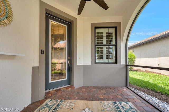 doorway to property featuring a ceiling fan and stucco siding