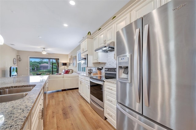 kitchen with ceiling fan, light hardwood / wood-style floors, stainless steel appliances, light stone counters, and backsplash