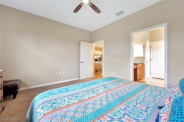 bedroom with light colored carpet, ensuite bathroom, and ceiling fan