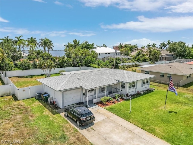 view of front of home featuring central AC, a front yard, a garage, and a water view