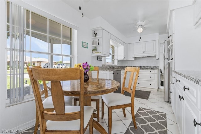 kitchen featuring light tile patterned flooring, dishwasher, white cabinets, light stone countertops, and tasteful backsplash