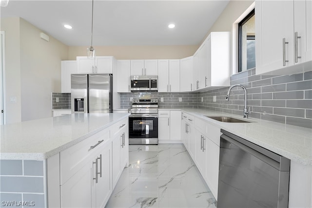 kitchen featuring white cabinetry, sink, light stone countertops, decorative light fixtures, and appliances with stainless steel finishes