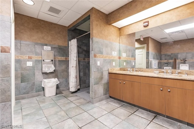 bathroom featuring a drop ceiling, vanity, a shower with shower curtain, and tile walls