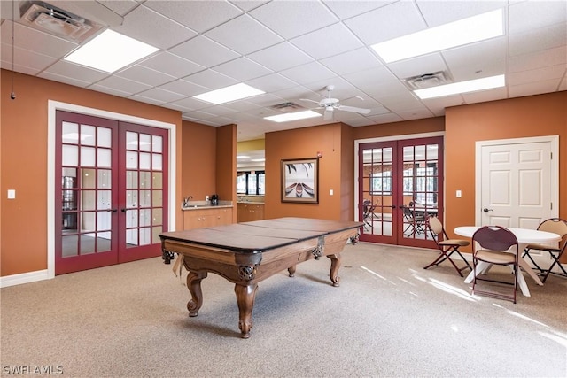 recreation room featuring ceiling fan, french doors, carpet floors, and a drop ceiling