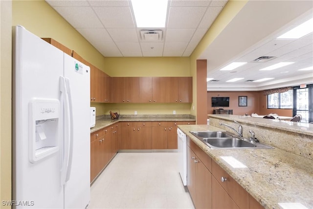 kitchen featuring light stone countertops, sink, a drop ceiling, and white appliances