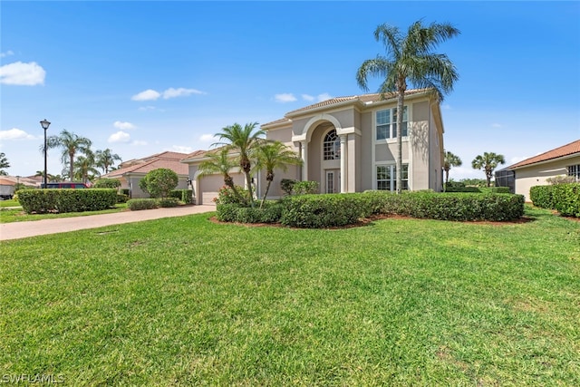 mediterranean / spanish-style house featuring a garage, driveway, a front yard, and stucco siding