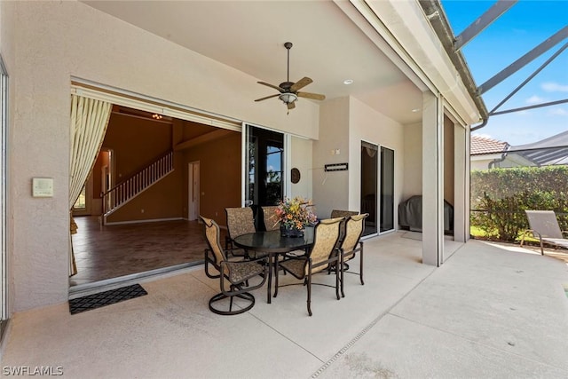 view of patio with ceiling fan and glass enclosure