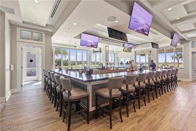 bar with a wealth of natural light, a high ceiling, visible vents, and light wood-style floors