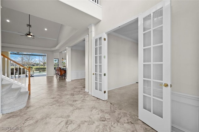 foyer featuring ceiling fan, decorative columns, ornamental molding, light carpet, and french doors