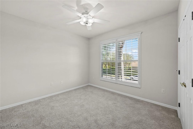 unfurnished room featuring a ceiling fan, light colored carpet, and baseboards